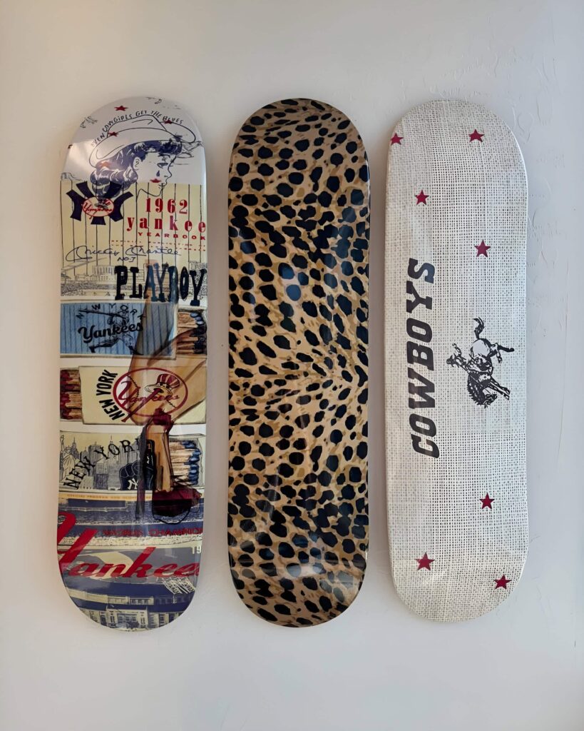 A trio of decorative skateboards mounted on a bedroom wall, featuring unique designs including a bold cheetah print, highlighting creative skateboard wall art for a girls' space.