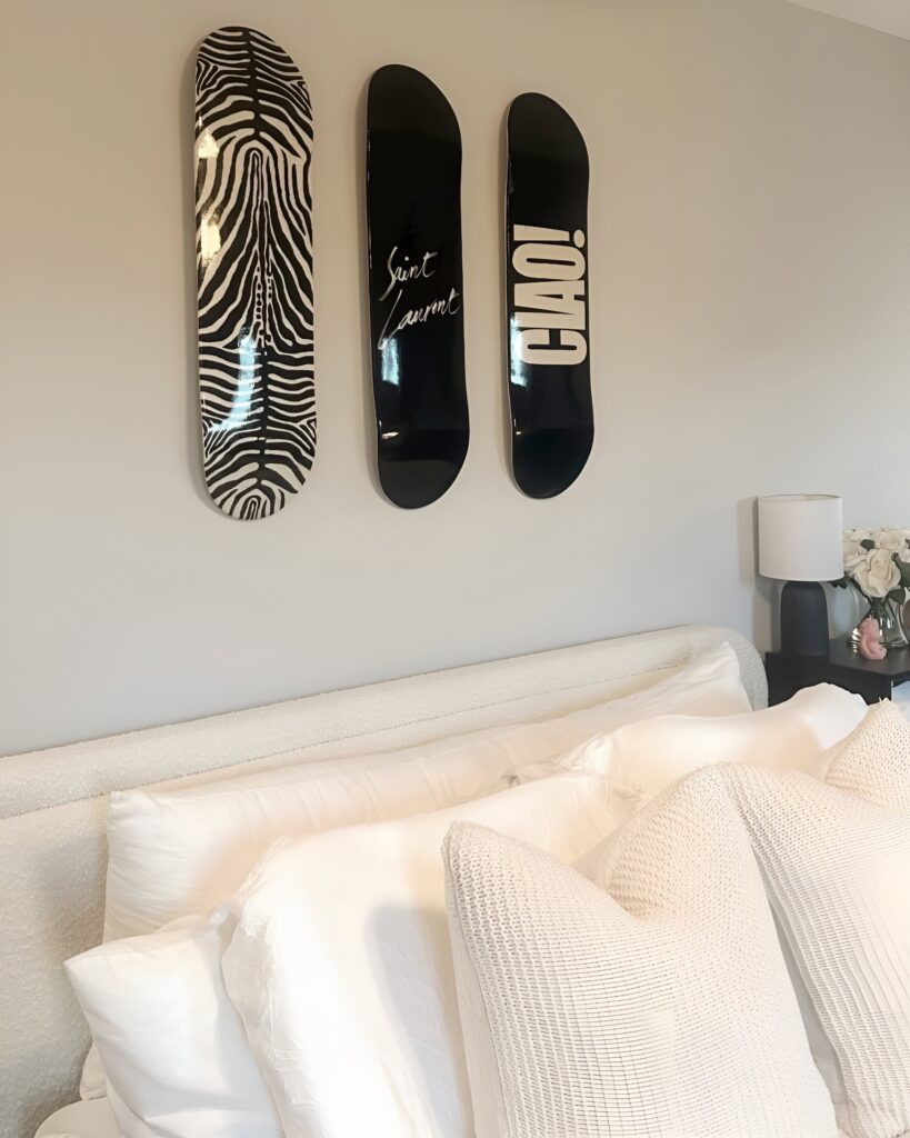 Skateboard wall art black and white set featuring bold zebra print and monochrome typography displayed above a cozy, neutral-toned bed in a girl's bedroom.