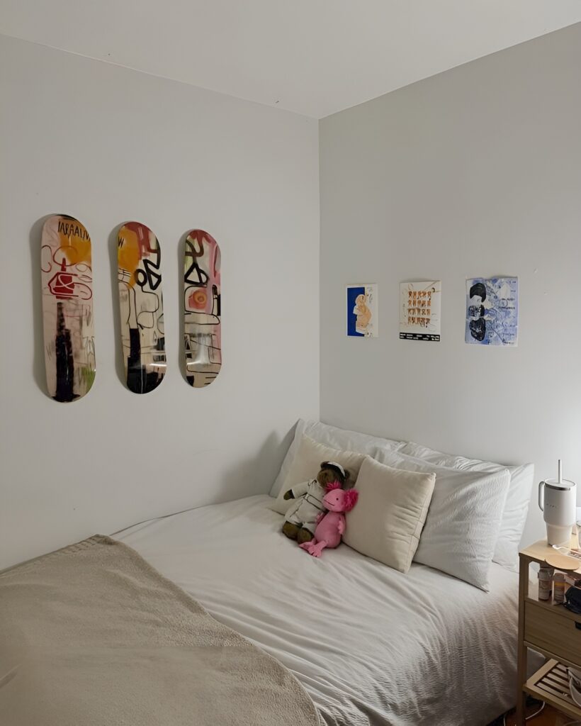 Cozy girls bedroom featuring Skateboard Wall Art above bed, surrounded by soft bedding, plush toys, and vibrant wall prints for a playful and artistic vibe.