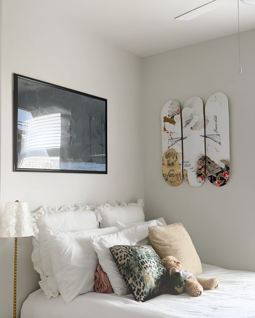 Skateboard wall art above bed features a romantic floral and script design, complementing the soft, feminine decor of a girl's bedroom.