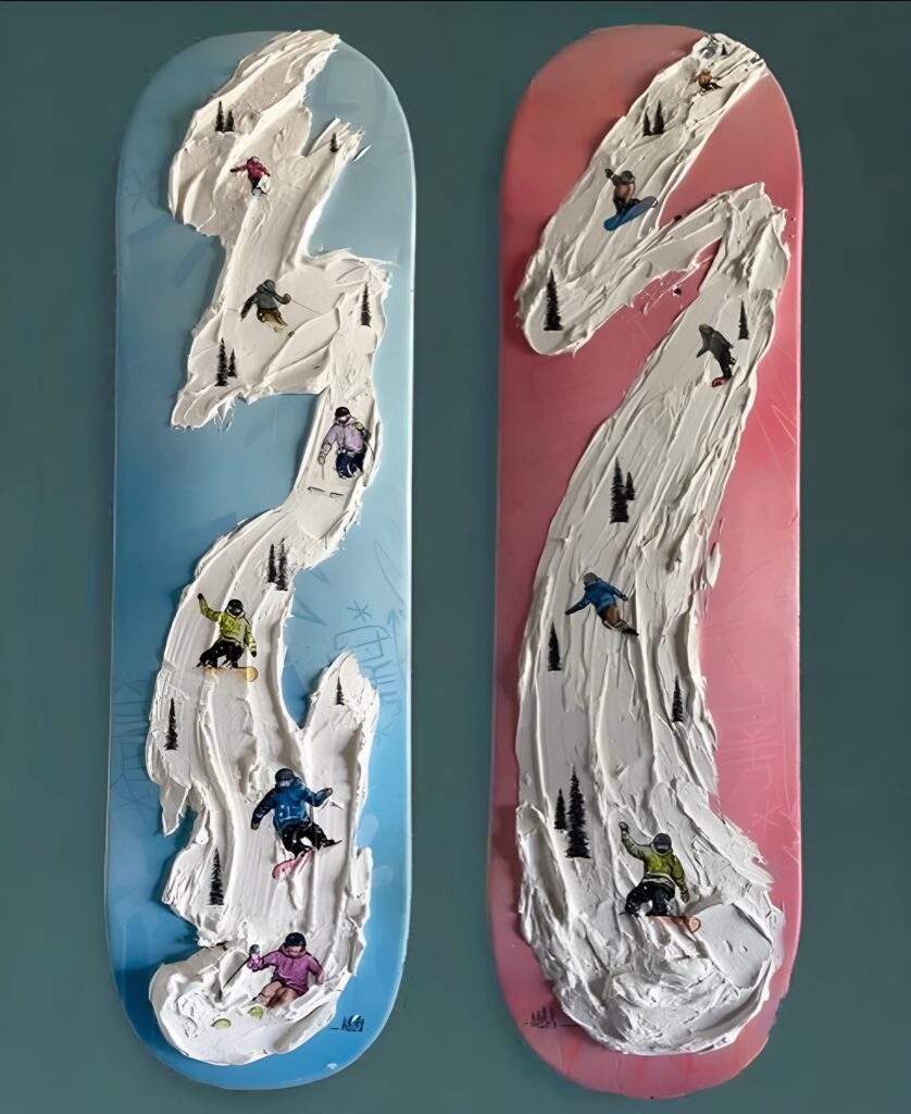 Two skateboard decks painted in pastel blue and pink feature textured 3D snow trails with miniature skiers and snowboarders, creating a unique and dynamic Skateboard Wall Art DIY for a girl's bedroom.