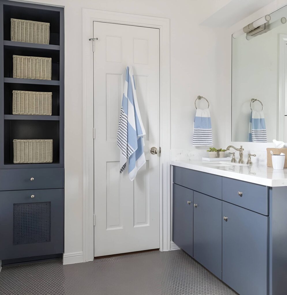 Modern boys' bathroom design with blue cabinets, built-in shelving, and striped blue and white towels for a clean coastal look.
