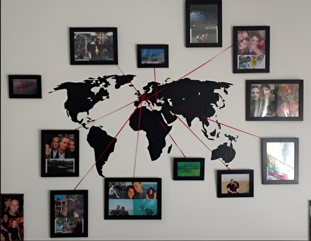 A creative wall display featuring a black world map surrounded by framed photos connected with red strings, forming a map with travel collage showcasing memorable moments from different locations.