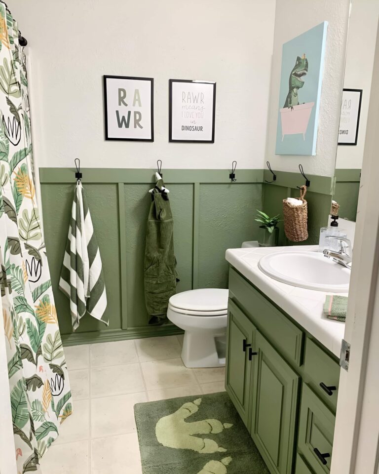 A playful and green-themed bathroom with dinosaur decor, framed prints, and towel hooks, offering creative bathroom design ideas for a boy's space.