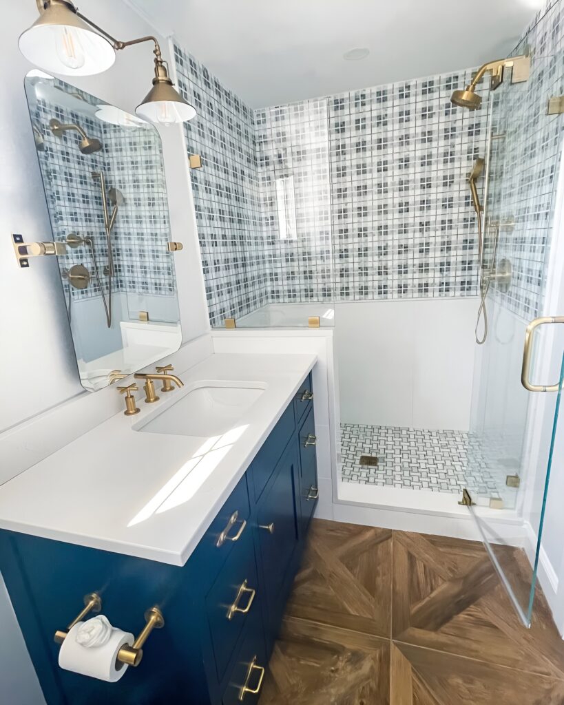 Modern kids bathroom design featuring navy blue vanity, brass fixtures, glass shower enclosure, and plaid wall tiles, ideal for a stylish boys' space.