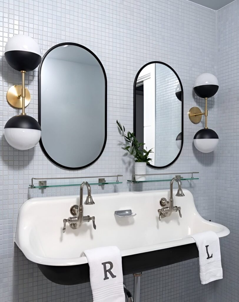 Chic and modern bathroom design for kids featuring a double sink with personalized towels, oval mirrors, globe sconces, and a small potted plant for a stylish touch.