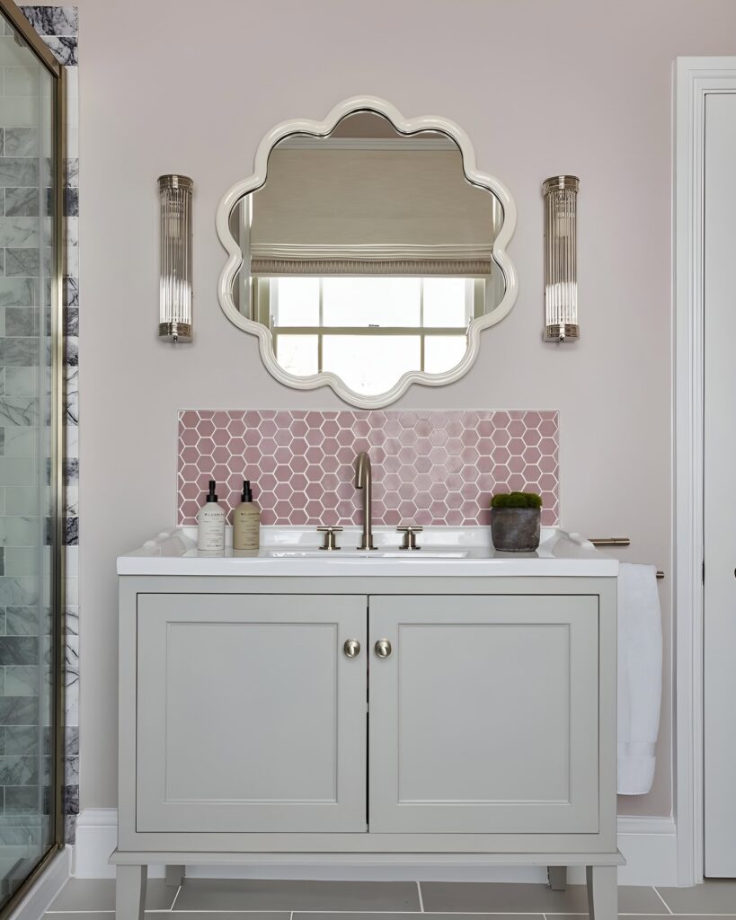 Elegant kids bathroom design with a soft pink color palette, scalloped mirror, hexagon tile backsplash, and a sleek vanity for a feminine touch.