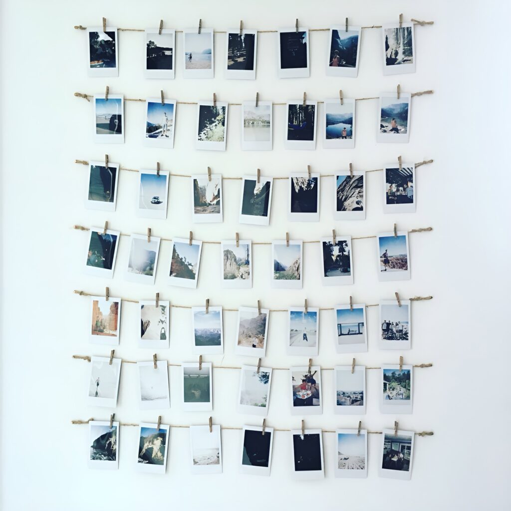 Polaroid-inspired pic display featuring rows of instant-style photos clipped to twine with mini clothespins, creating a simple and creative wall art arrangement.