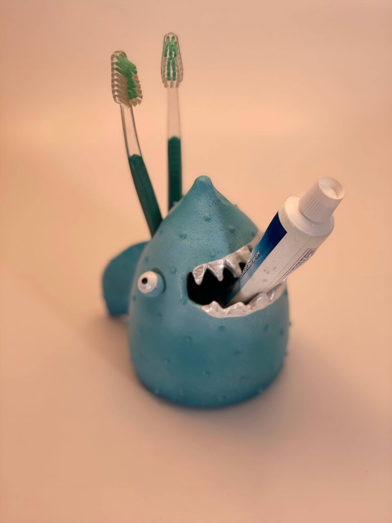 Creative boys' bathroom design featuring a playful blue shark-shaped toothbrush and toothpaste holder to make brushing fun for kids.