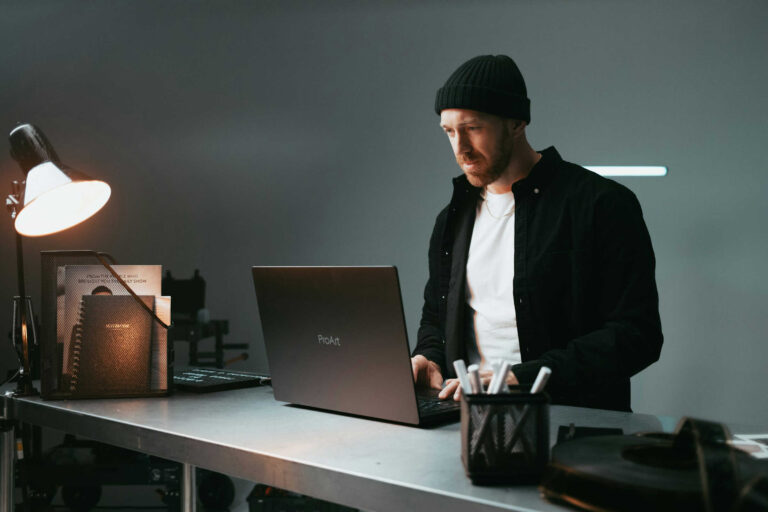 Entrepreneur using laptop to work on AI prompt for digital product ideas in a modern workspace.