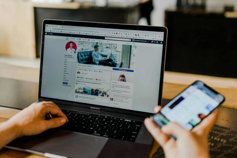 Person using laptop and phone to manage Facebook page, showing how to earn money from Facebook pages 2025.