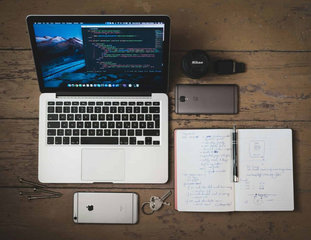 Laptop, smartphone, and handwritten notes on a desk, representing research and planning on how to validate side project ideas.
